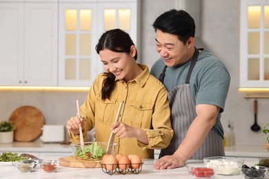 Happy lovely couple cooking together in kitchen