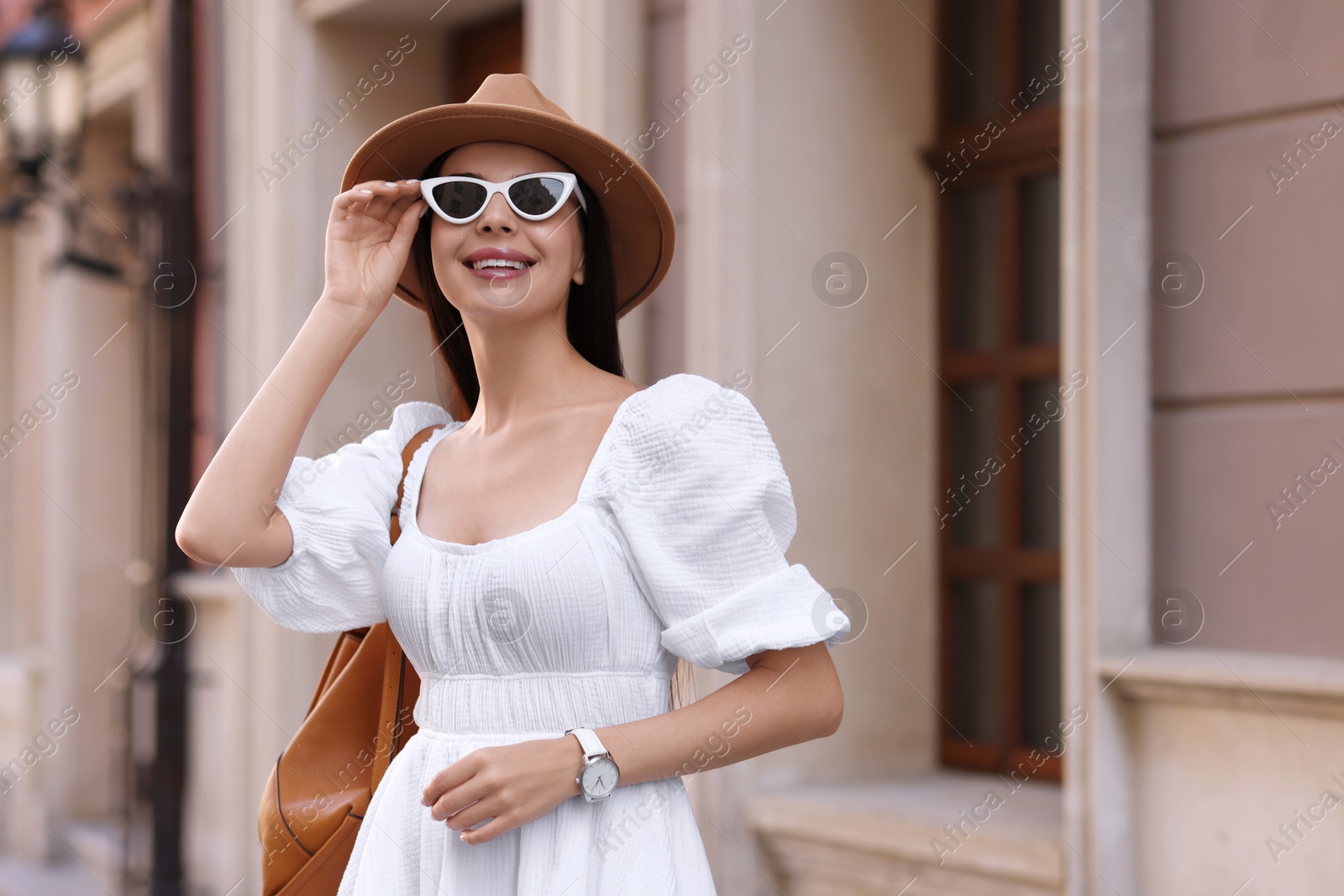 Photo of Smiling woman in stylish hat and sunglasses on city street