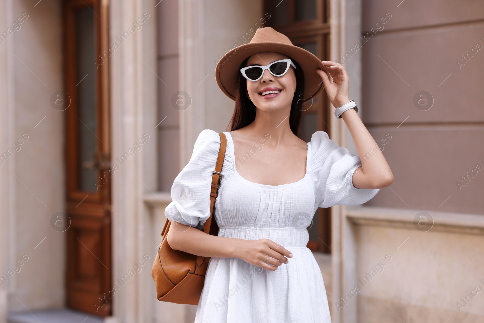 Photo of Smiling woman in stylish hat and sunglasses on city street