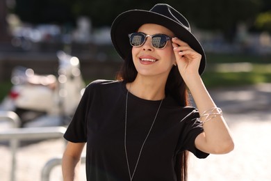 Photo of Smiling woman in stylish black hat and sunglasses outdoors