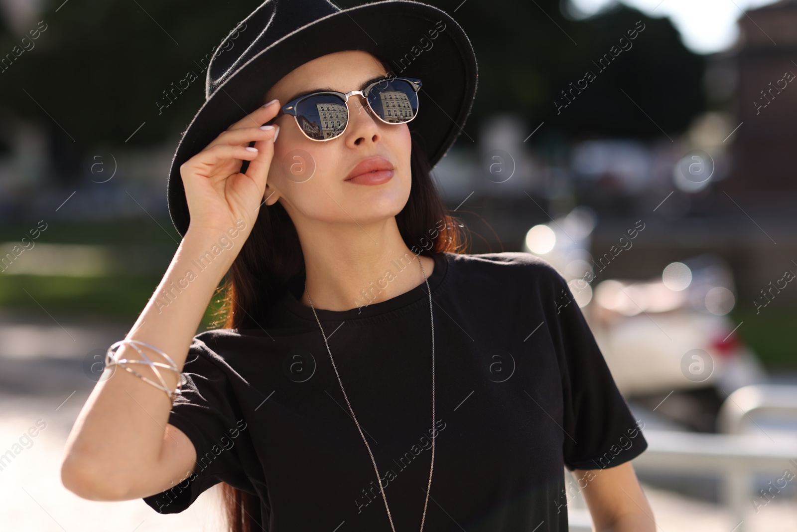 Photo of Young woman in stylish black hat and sunglasses outdoors