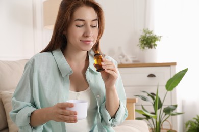 Woman with bottle of essential oil and aroma diffuser at home