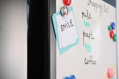 Photo of Magnetic board with shopping list and notes on refrigerator, closeup