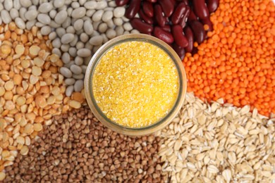 Photo of Dry cornmeal in jar surrounded by different cereals and legumes, top view