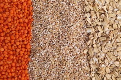 Photo of Red lentils, wheat groats and oat flakes as background, top view