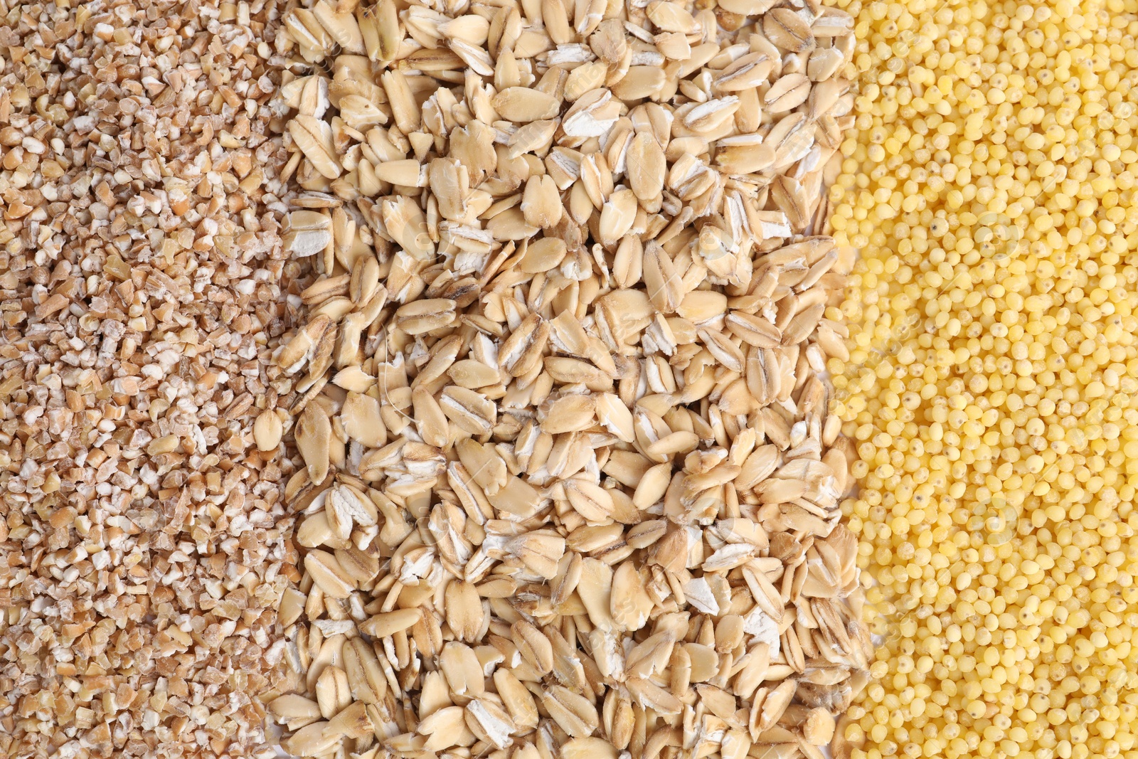 Photo of Oat flakes, wheat and millet groats as background, top view