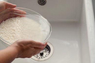 Woman rinsing rice in bowl above sink, closeup. Space for text