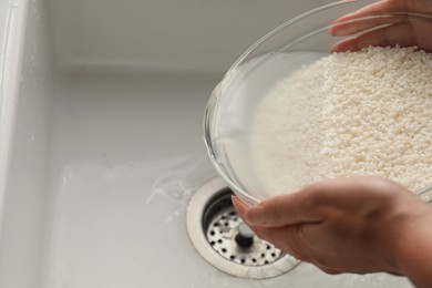 Photo of Woman rinsing rice in bowl above sink, closeup. Space for text