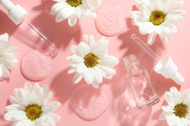 Photo of Beautiful daisy flowers, cosmetic bottle, pipettes and drops of serum on pink background, flat lay