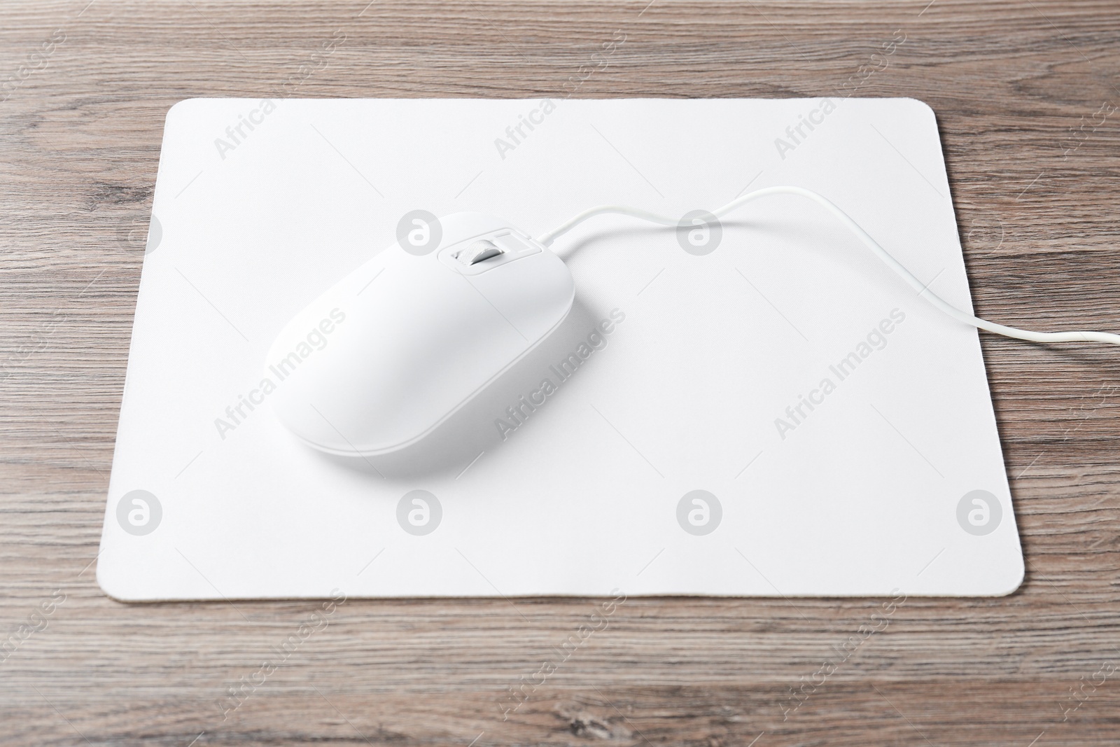 Photo of Computer mouse with mousepad on wooden desk