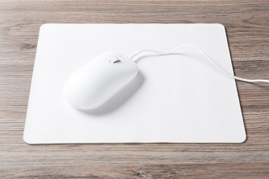 Photo of Computer mouse with mousepad on wooden desk