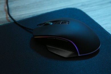 Photo of Computer mouse with mousepad on wooden table, closeup