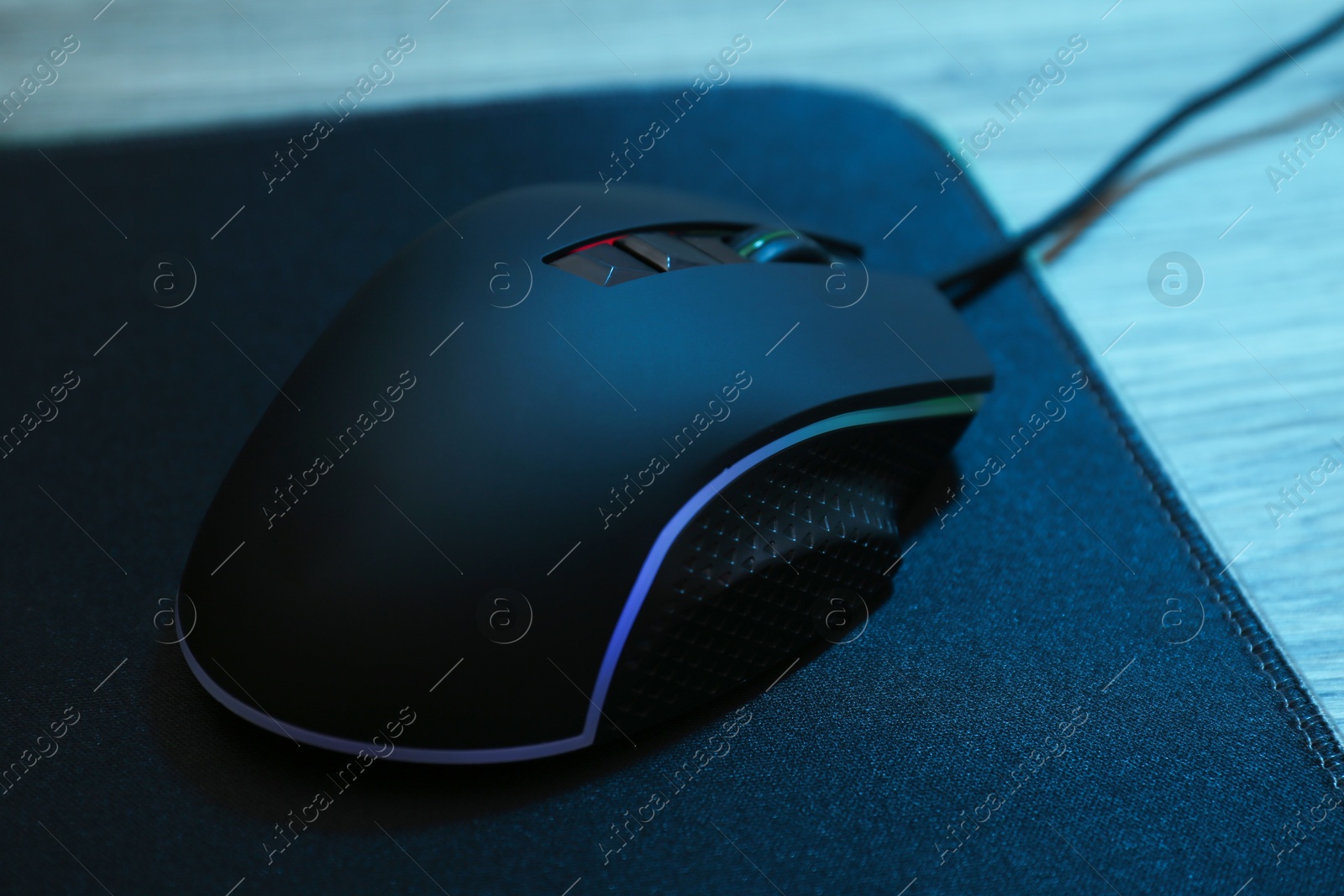 Photo of Computer mouse with mousepad on wooden table, closeup