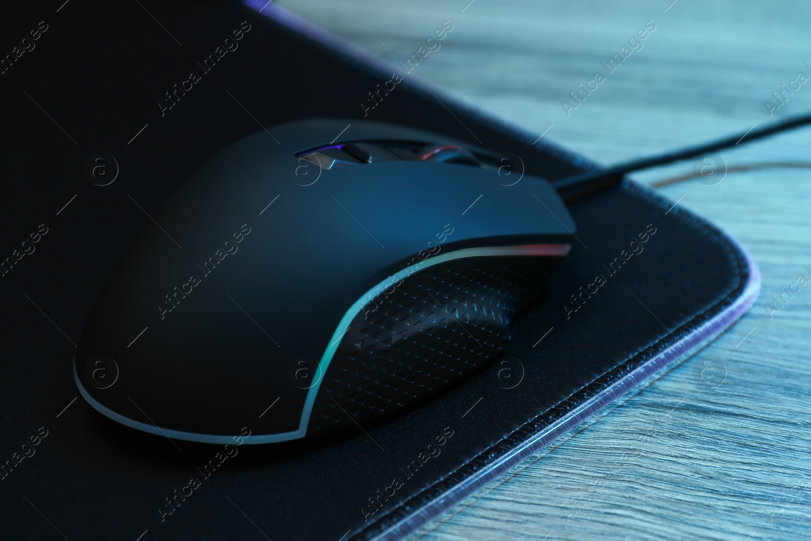 Photo of Computer mouse with mousepad on wooden table, closeup