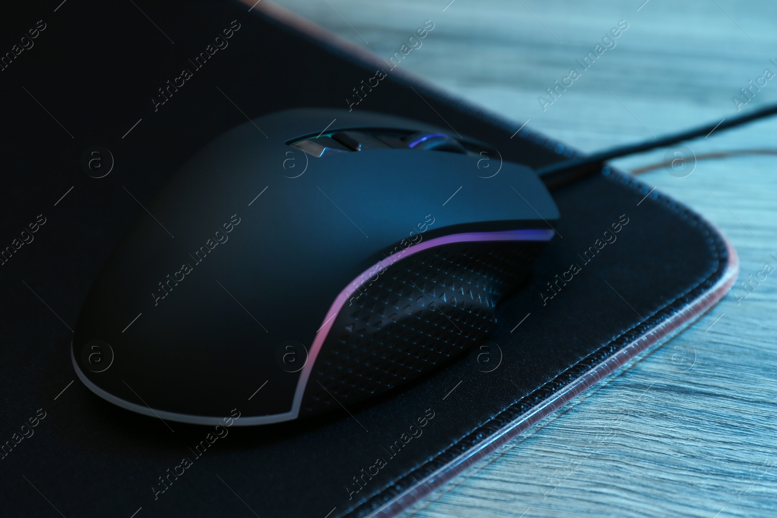 Photo of Computer mouse with mousepad on wooden table, closeup