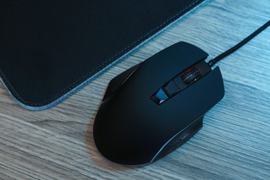 Photo of Computer mouse with mousepad on wooden table, flat lay