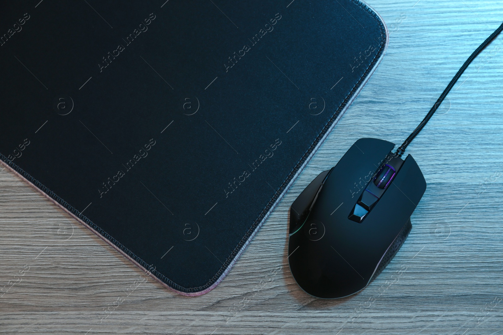 Photo of Computer mouse with mousepad on wooden table, flat lay