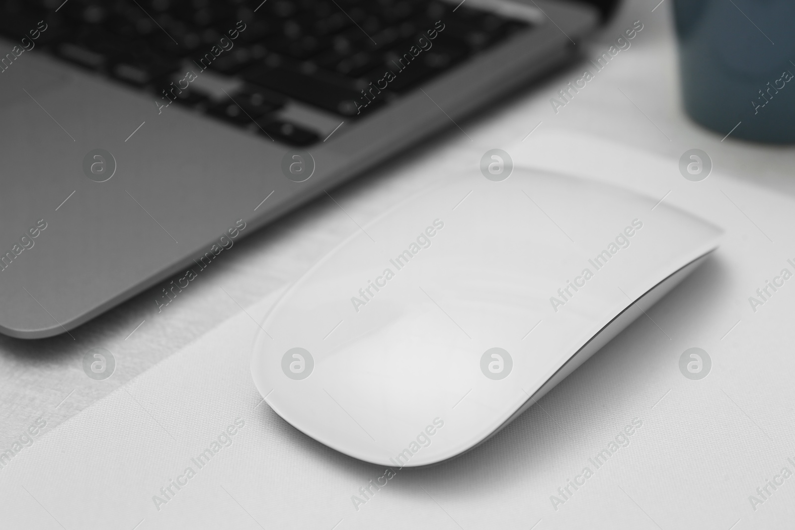 Photo of Computer mouse with mousepad and laptop on light wooden table, closeup