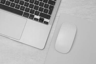 Photo of Computer mouse with mousepad and laptop on light wooden table, flat lay