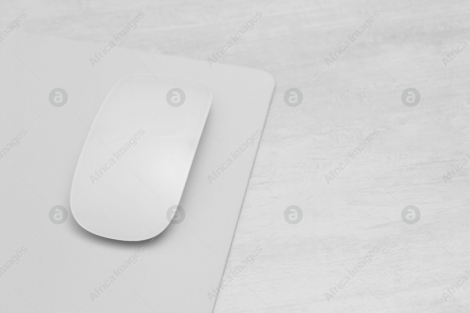 Photo of Computer mouse with mousepad on light wooden table, closeup. Space for text