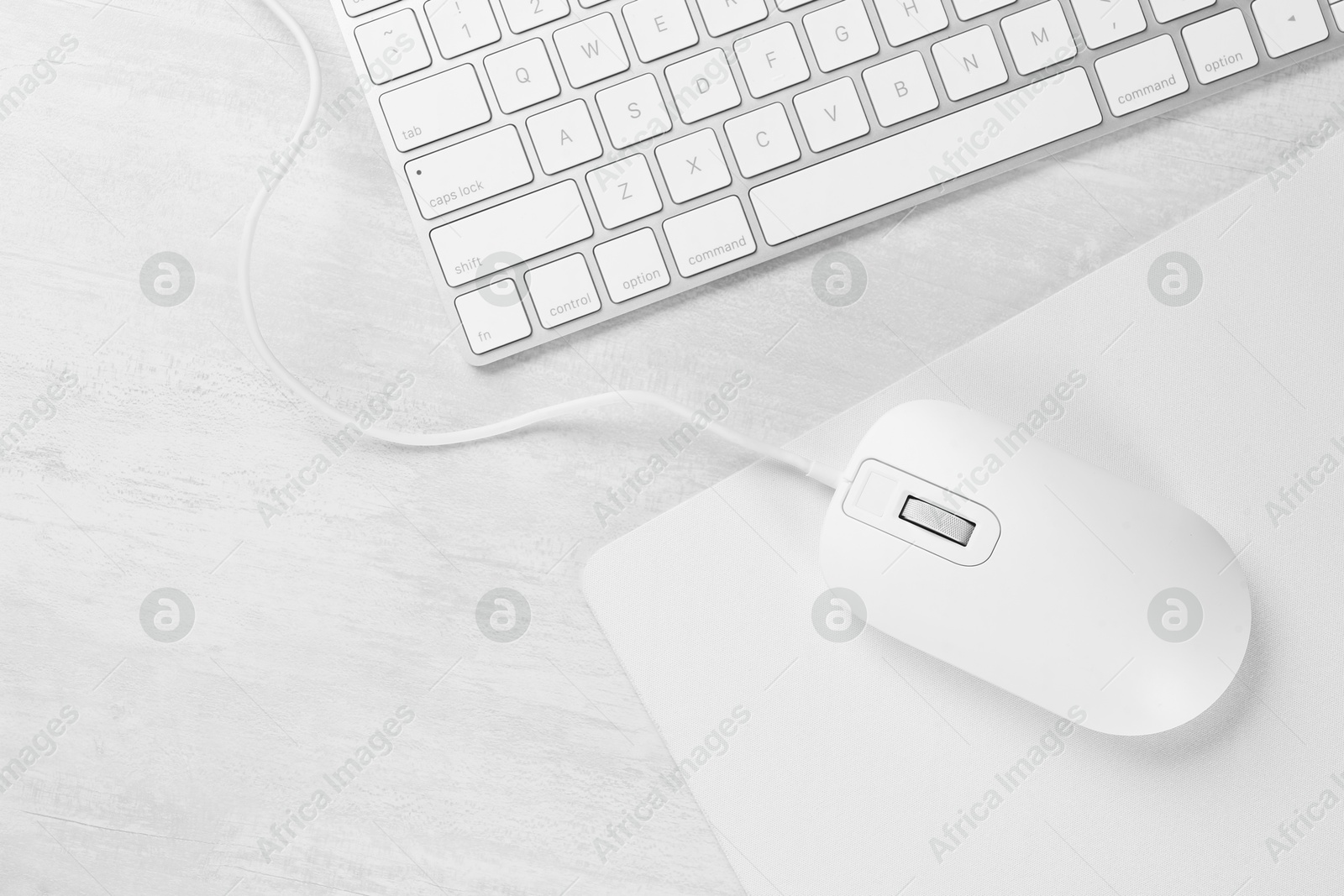 Photo of Computer mouse with mousepad and keyboard on light wooden table, flat lay