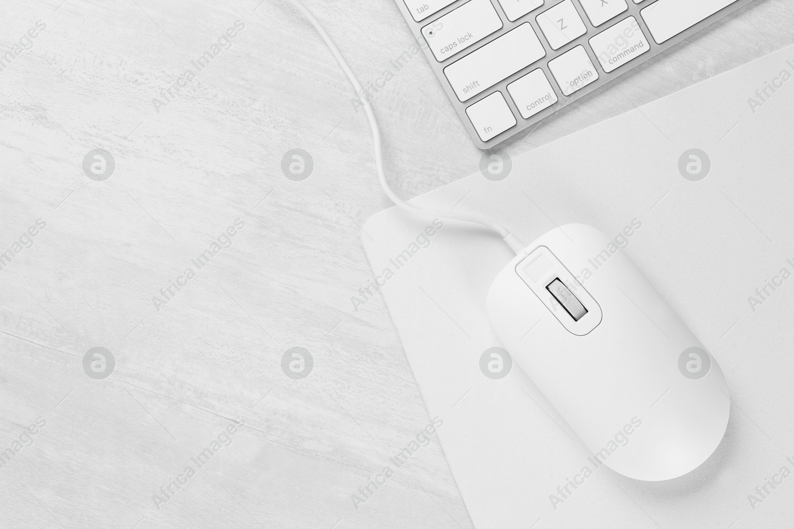 Photo of Computer mouse with mousepad and keyboard on light wooden table, flat lay. Space for text