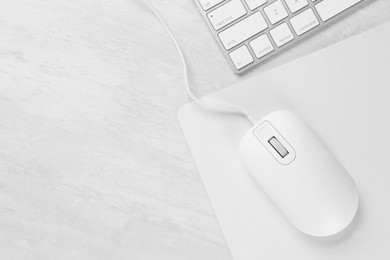 Photo of Computer mouse with mousepad and keyboard on light wooden table, flat lay. Space for text