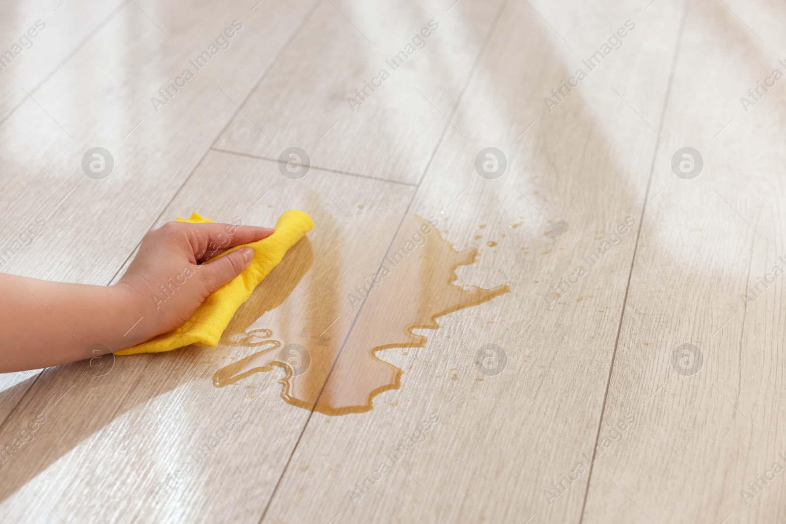 Photo of Woman wiping puddle of spilled drink on floor, closeup