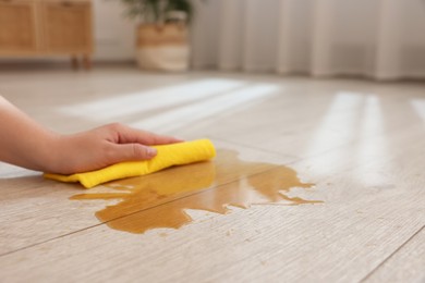 Photo of Woman wiping puddle of spilled drink on floor, closeup