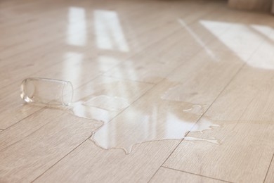 Photo of Glass with spilled drink on wooden floor