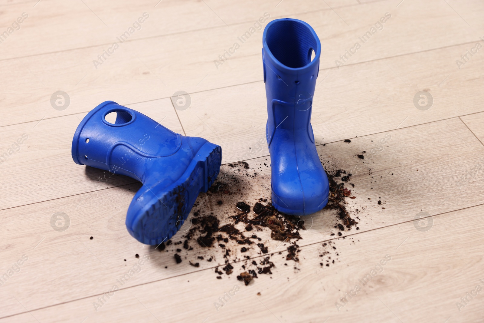 Photo of Rubber boots with mud on wooden floor