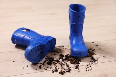 Photo of Rubber boots with mud on wooden floor