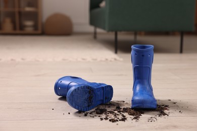 Photo of Rubber boots with mud on wooden floor