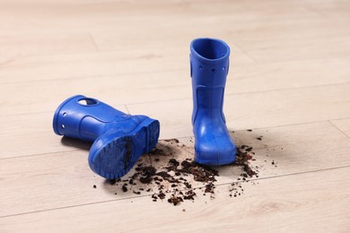 Photo of Rubber boots with mud on wooden floor