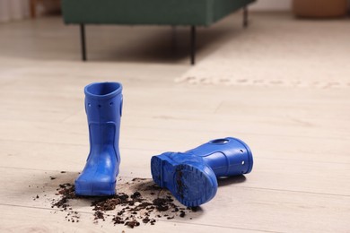 Photo of Rubber boots with mud on wooden floor