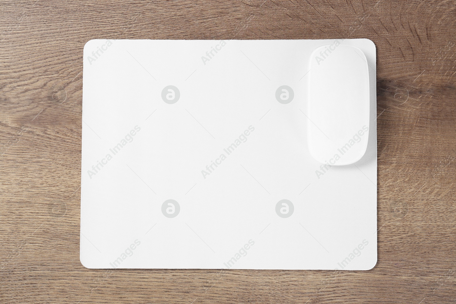 Photo of Computer mouse with mousepad on wooden table, top view