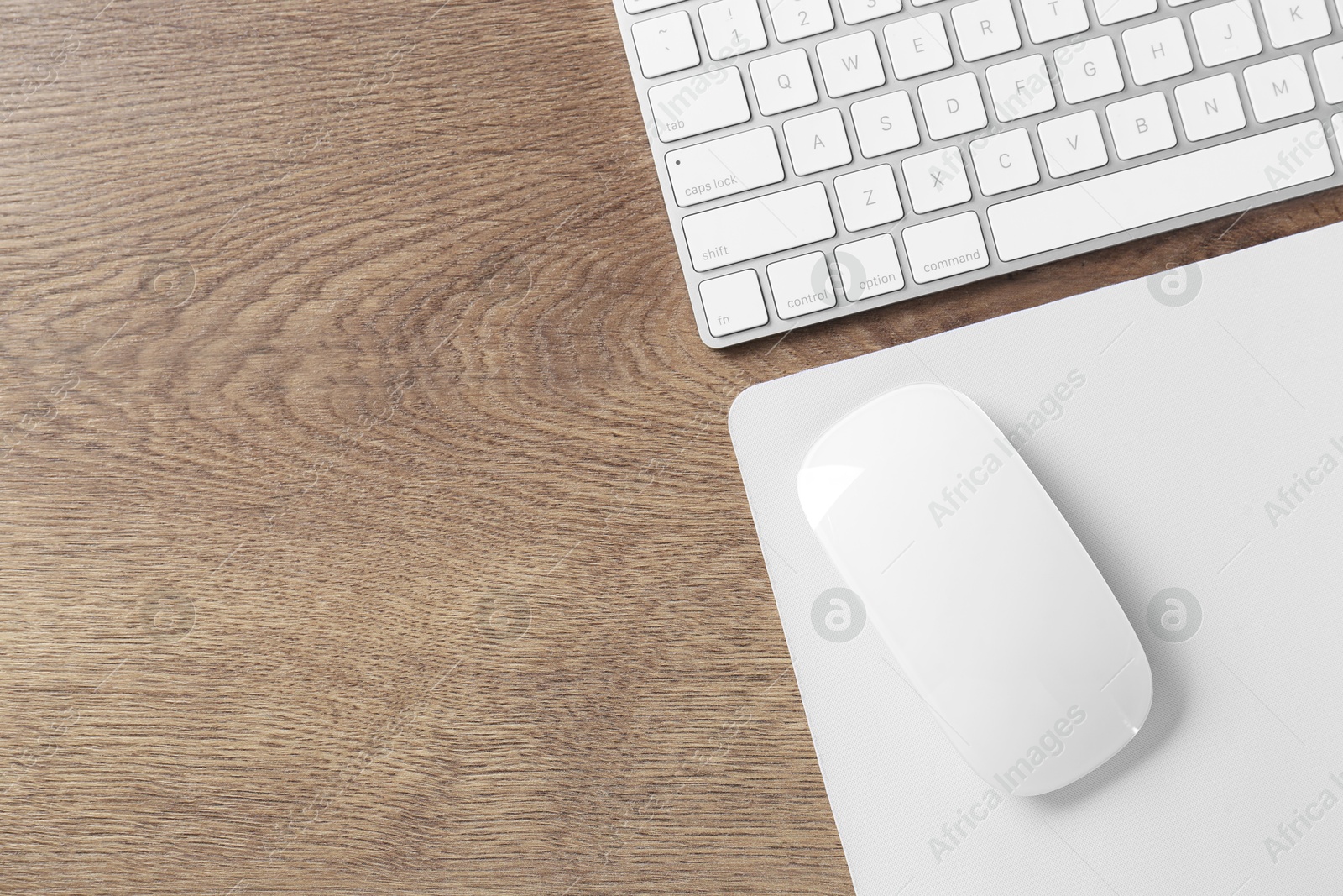 Photo of Computer mouse with mousepad and keyboard on wooden table, flat lay. Space for text