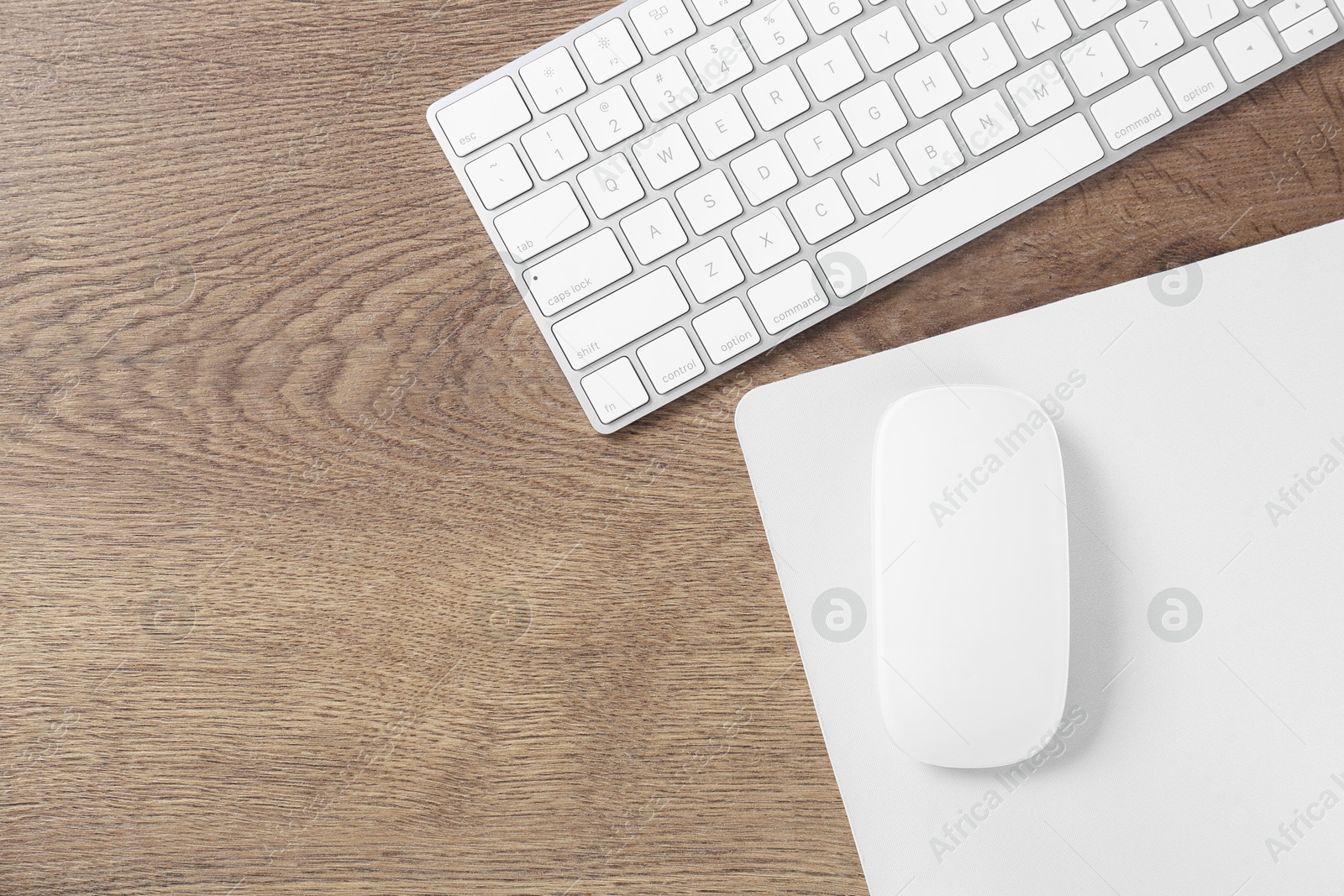 Photo of Computer mouse with mousepad and keyboard on wooden table, flat lay. Space for text