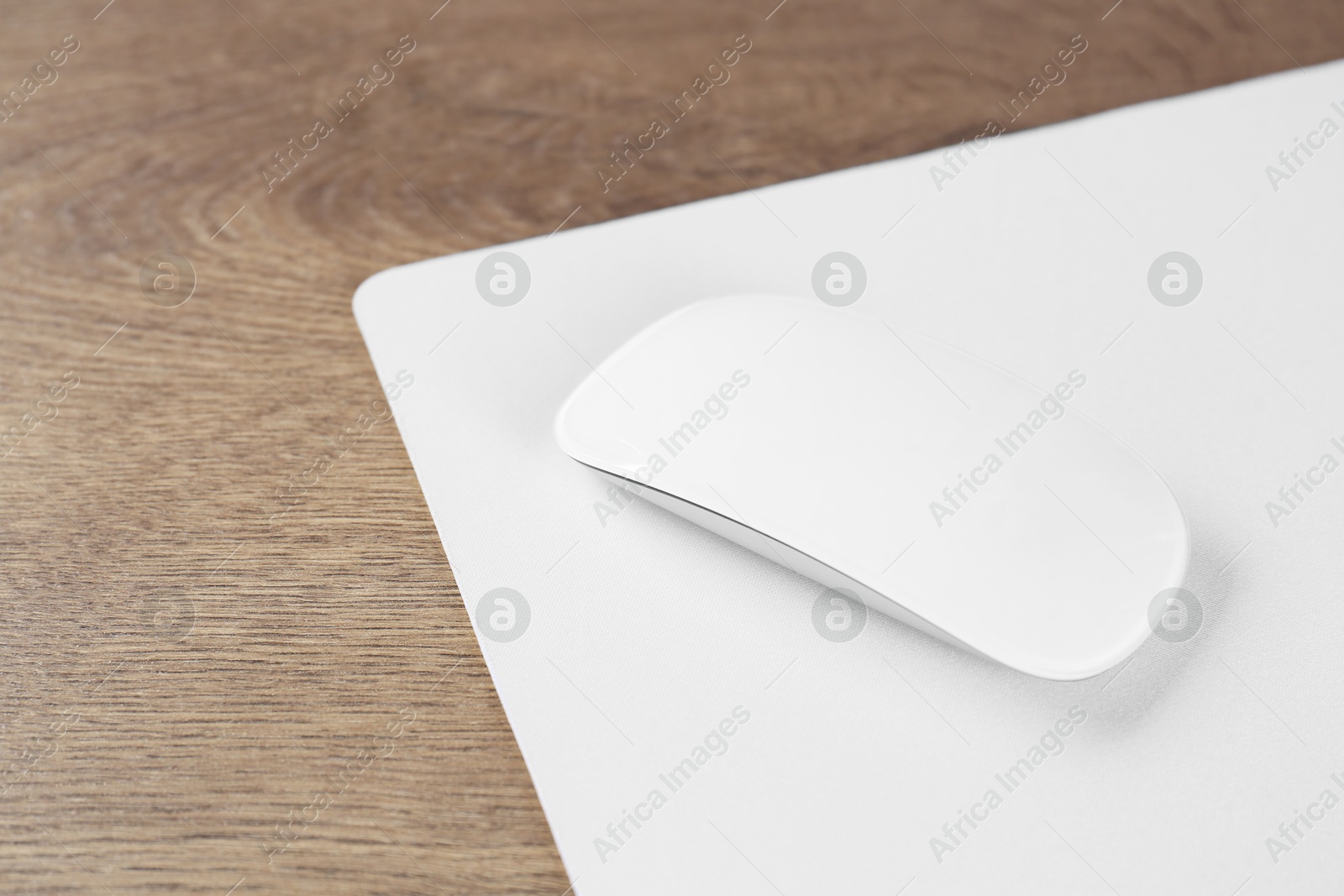 Photo of Computer mouse with mousepad on wooden table