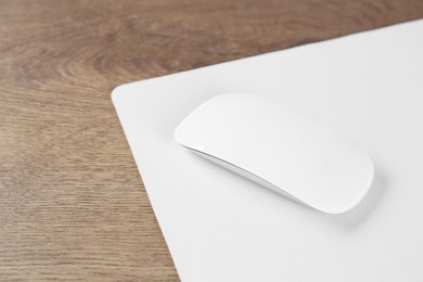 Photo of Computer mouse with mousepad on wooden table