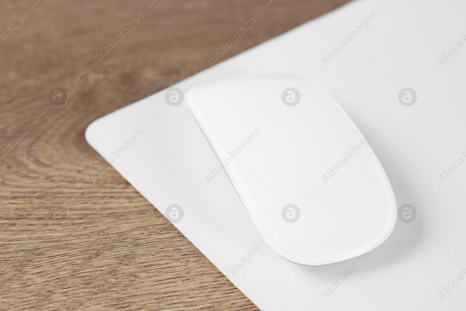 Photo of Computer mouse with mousepad on wooden table, closeup