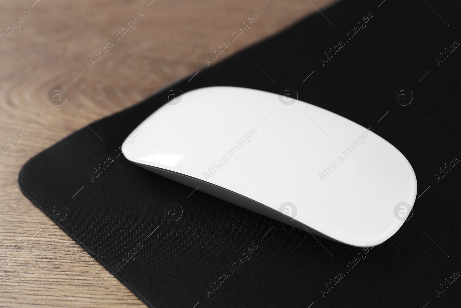 Photo of Computer mouse with mousepad on wooden table, closeup