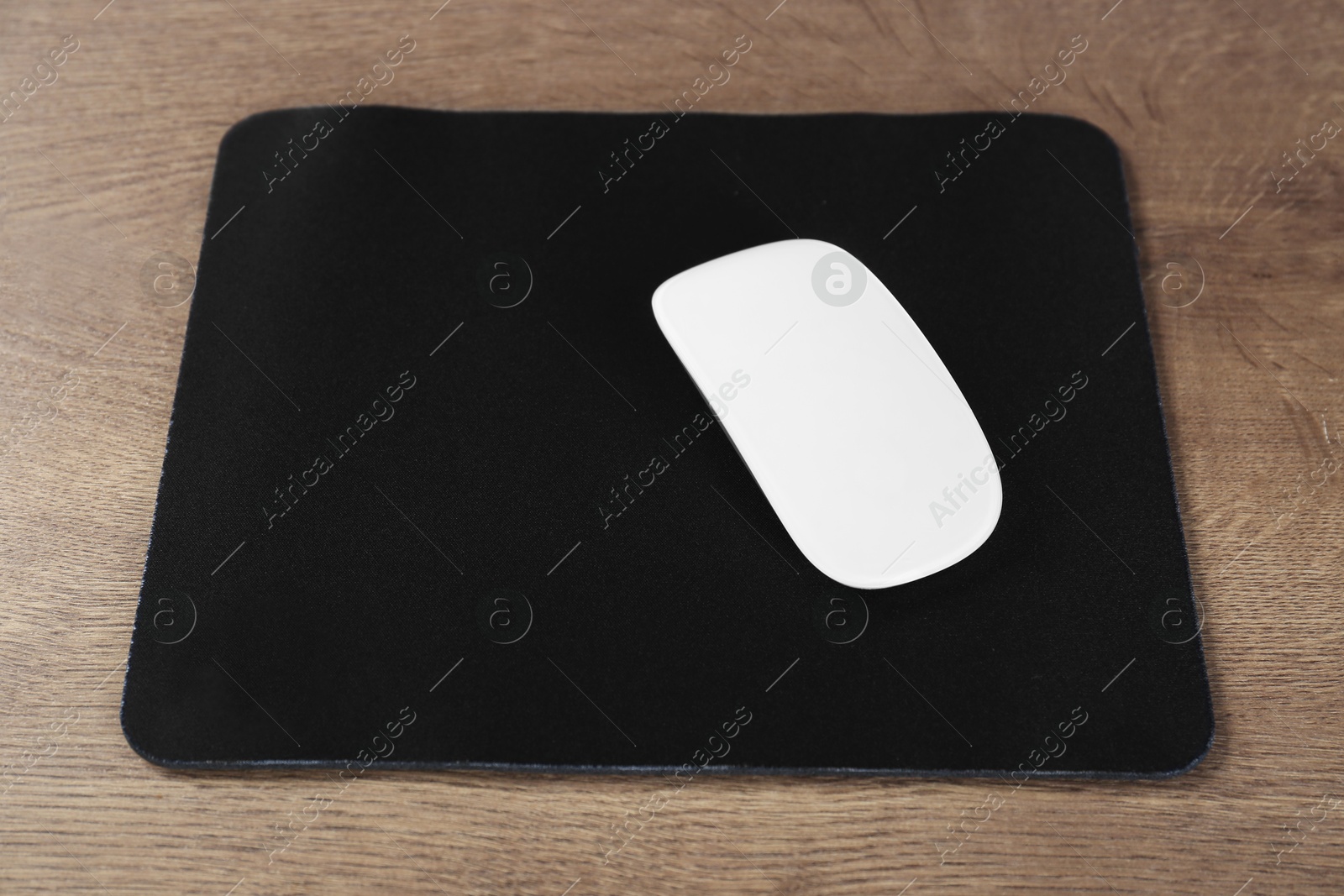 Photo of Computer mouse with mousepad on wooden table