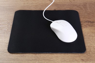 Photo of Computer mouse with mousepad on wooden table