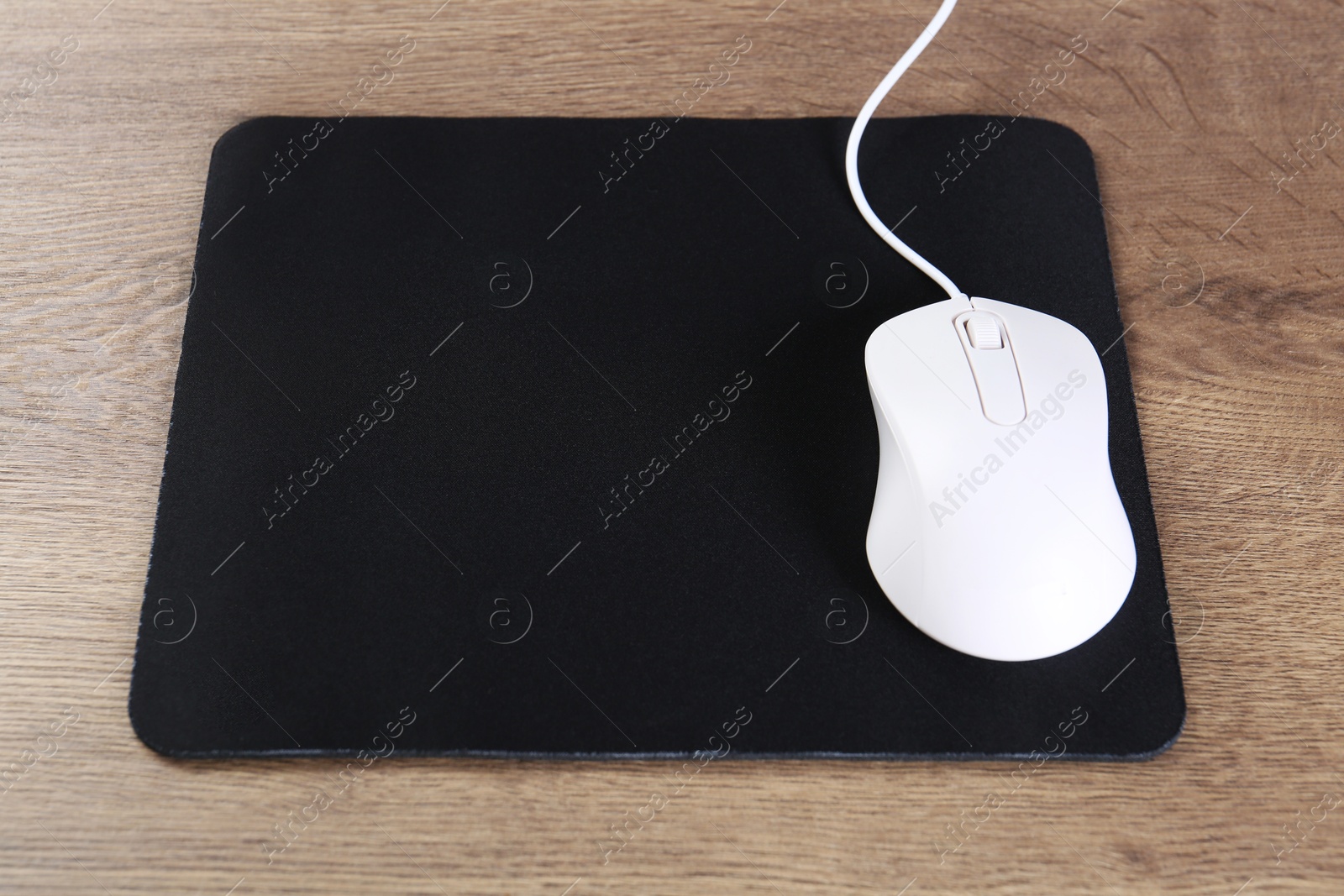 Photo of Computer mouse with mousepad on wooden table