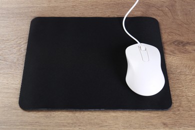 Photo of Computer mouse with mousepad on wooden table