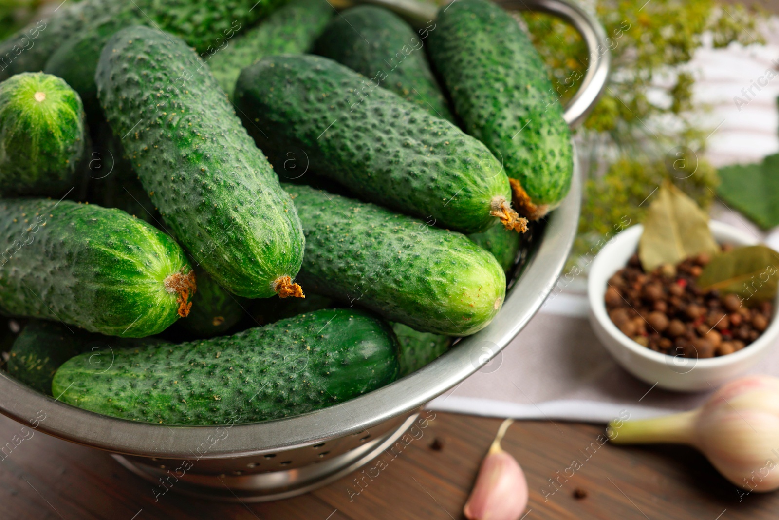 Photo of Fresh green cucumbers in colander on table, closeup