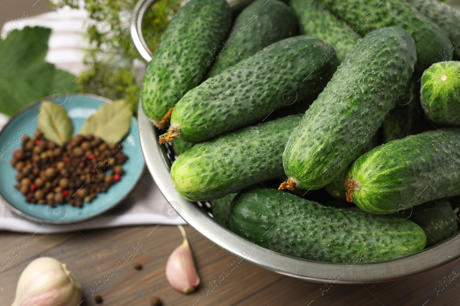 Photo of Fresh green cucumbers in colander on table, closeup