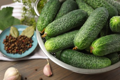 Photo of Fresh green cucumbers in colander on table, closeup