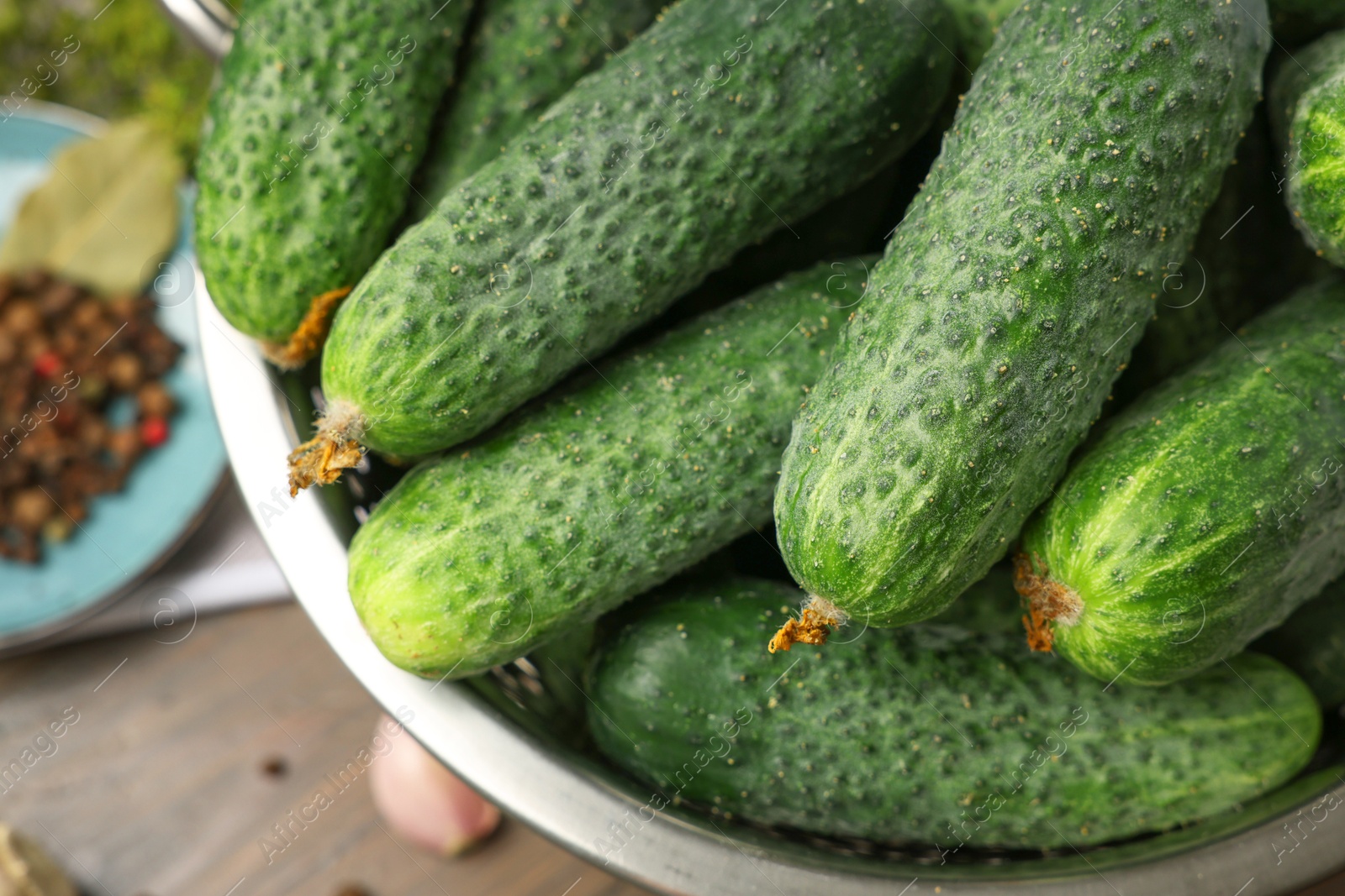 Photo of Fresh green cucumbers in colander on table, closeup